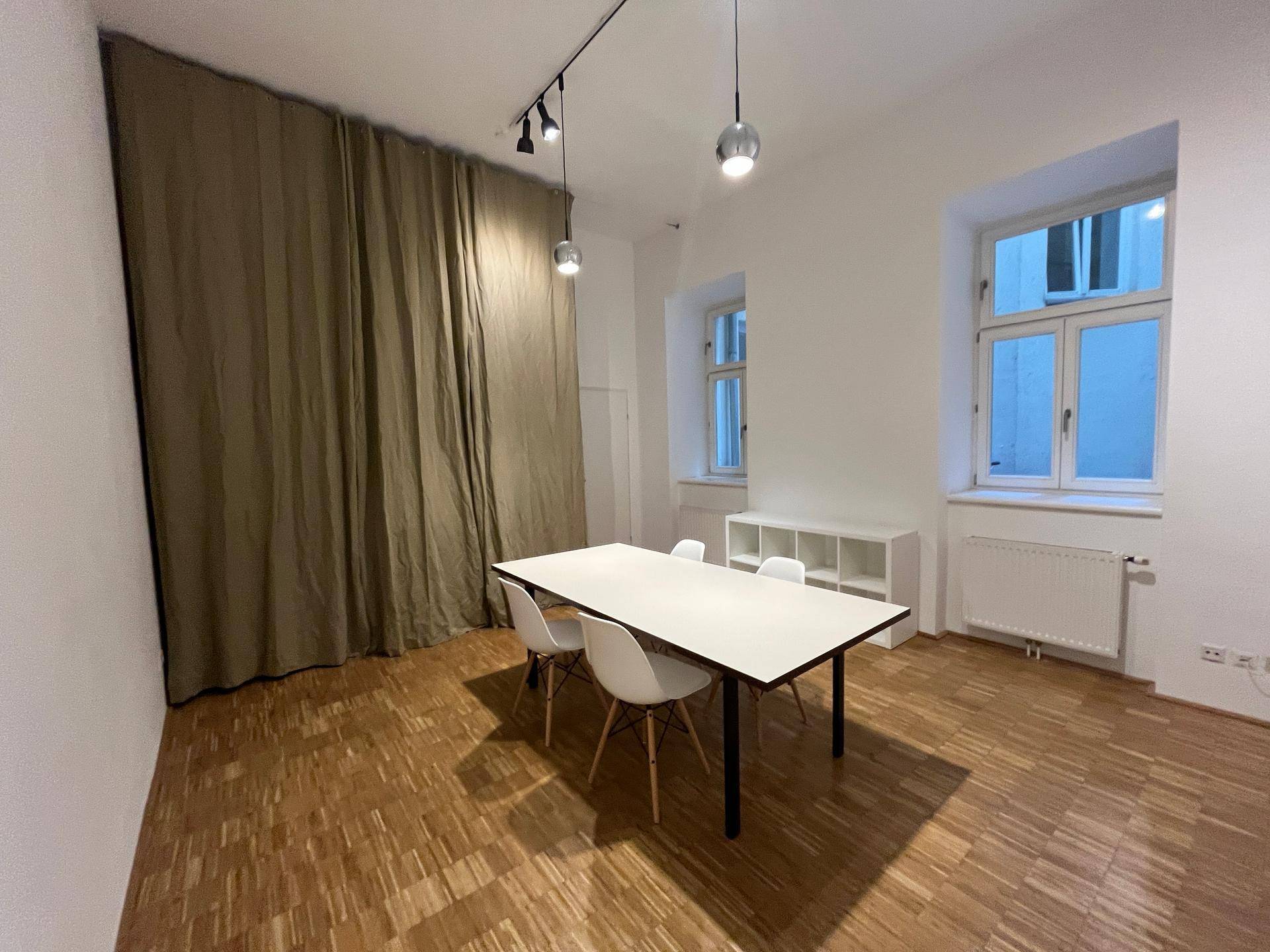 Essbereich mit großen Fenstern, Heizkörper und einem langen Tisch mit Stühlen.