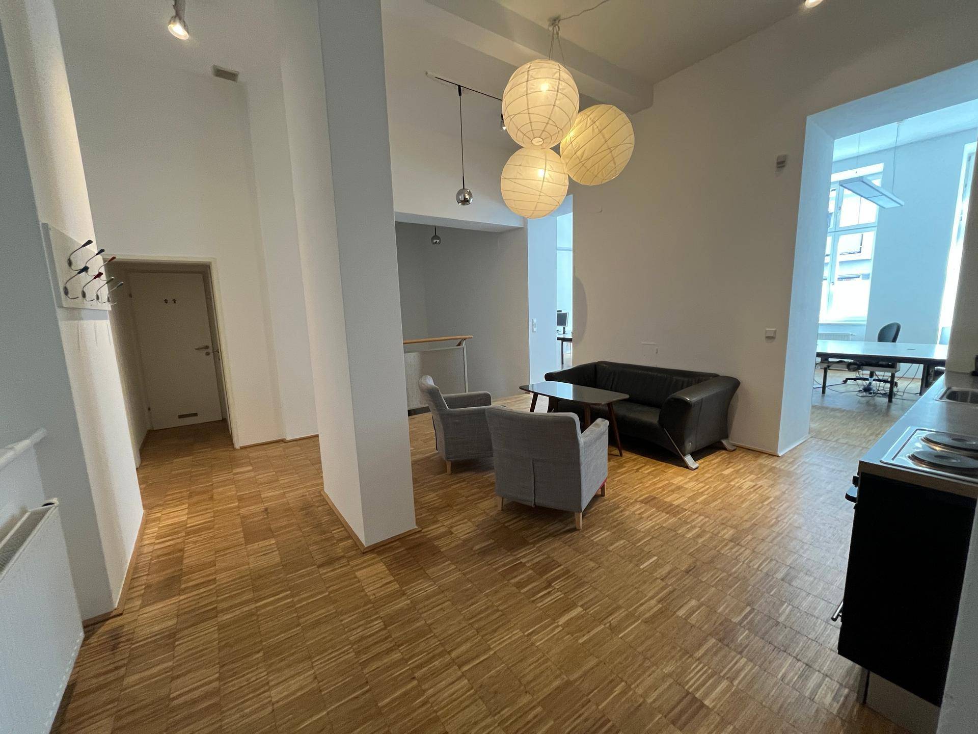 Geräumiger Wohnbereich mit offener Gestaltung, Holzboden und Blick in den Bürobereich.