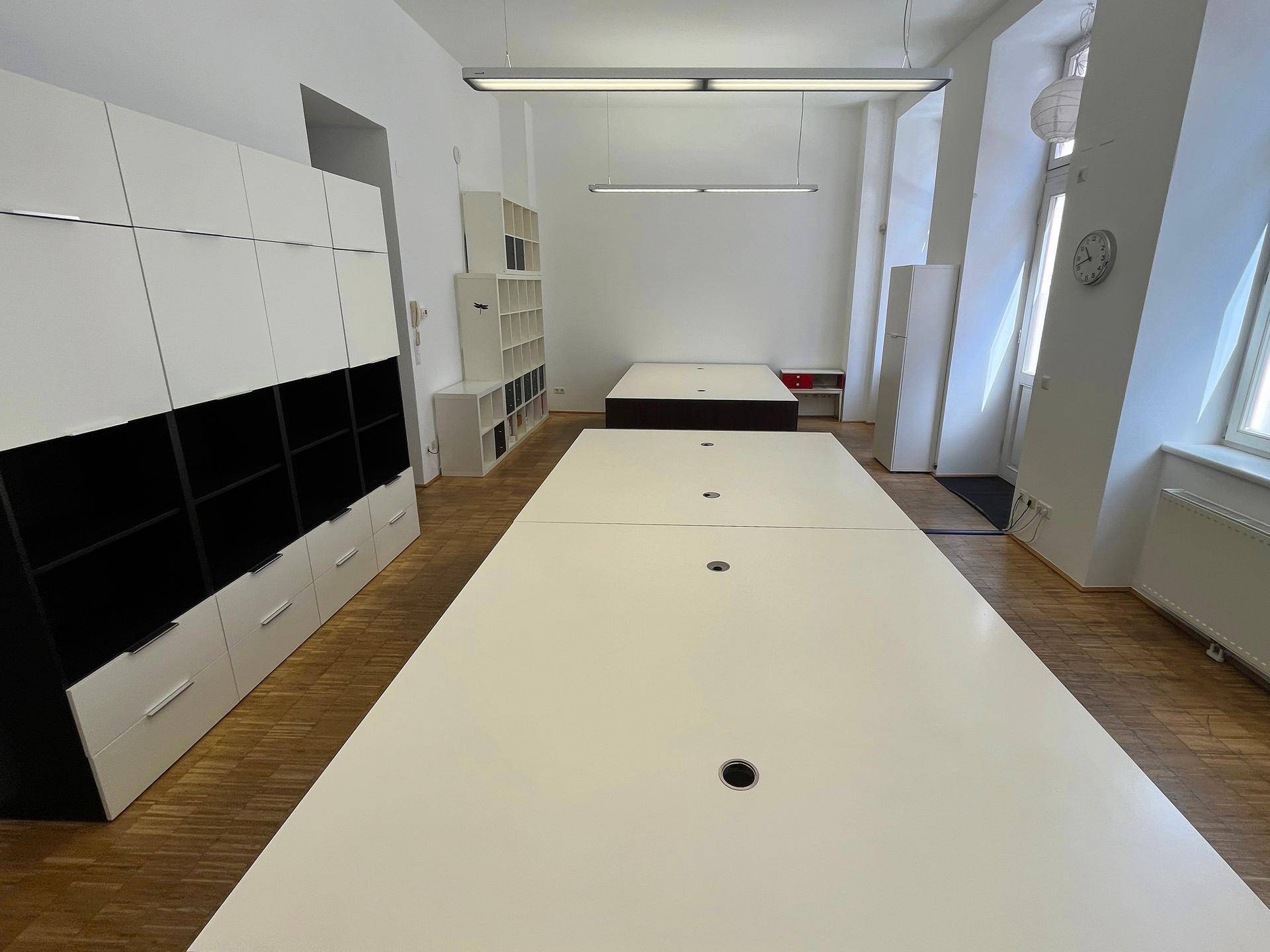 Weitläufiges Büro mit langen Schreibtischen, viel Stauraum und großen Fenstern.
