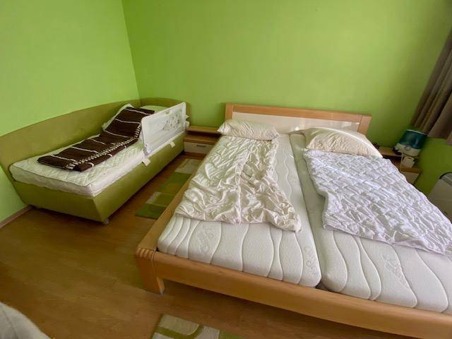 Schlafzimmer mit zwei Betten und grünen Wänden, ideal als Kinder- oder Gästezimmer.