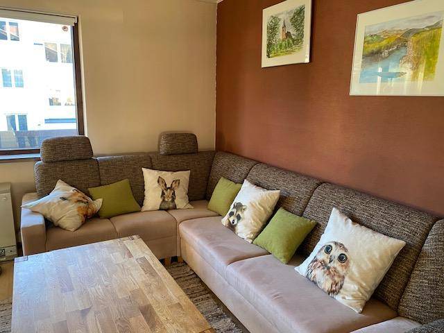 Geräumiges Wohnzimmer mit großem Ecksofa, Holztisch und Bildern an der braunen Wand.