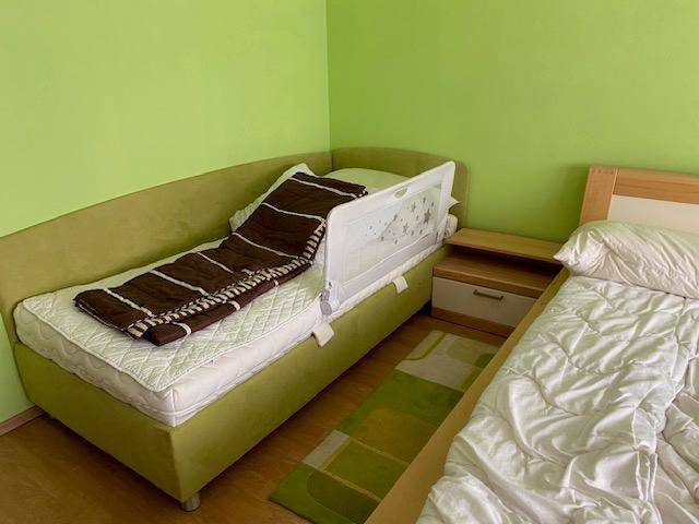 Einzelbett mit Kindersicherung und Nachttisch in einem hellgrünen Schlafzimmer.
