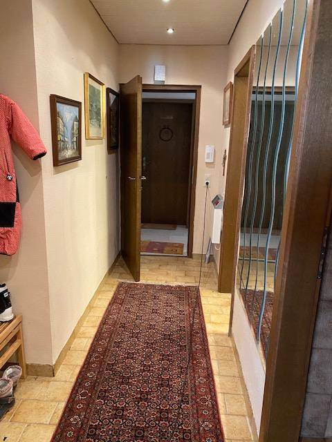 Einladender Flur mit Teppichläufer, Spiegelfläche und der Eingangstür zur Wohnung.