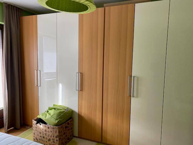 Geräumige Kleiderschränke in Holz- und Weißtönen bieten viel Stauraum im Schlafzimmer.