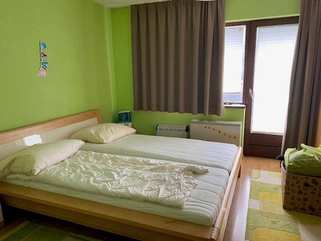 Helles Schlafzimmer mit zwei Einzelbetten, grünen Wänden und Zugang zu einem Balkon.