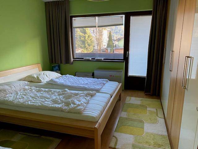 Helles Schlafzimmer mit zwei Betten, grünen Wänden und Blick auf die Umgebung.