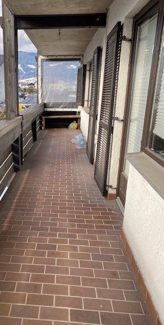 Langer Balkon mit braunen Fliesen und Holzbalken, ideal für entspannte Stunden im Freien.