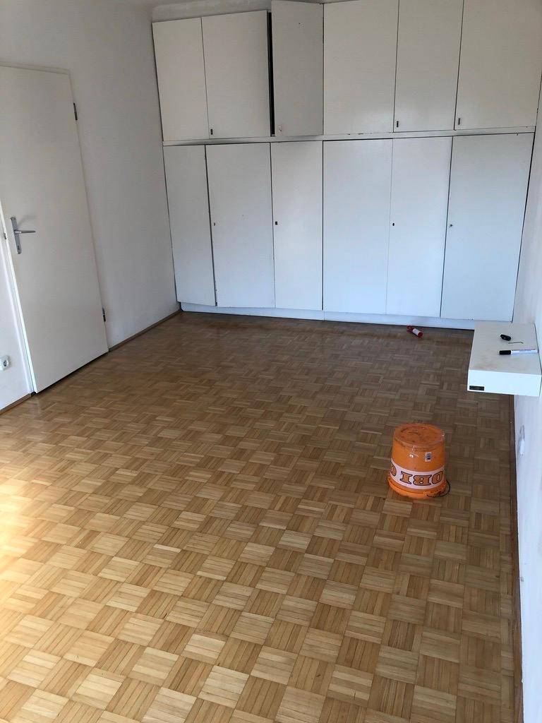 Schlafzimmer mit Parkettboden und praktischen, deckenhohen Einbauschränken entlang einer Wand.