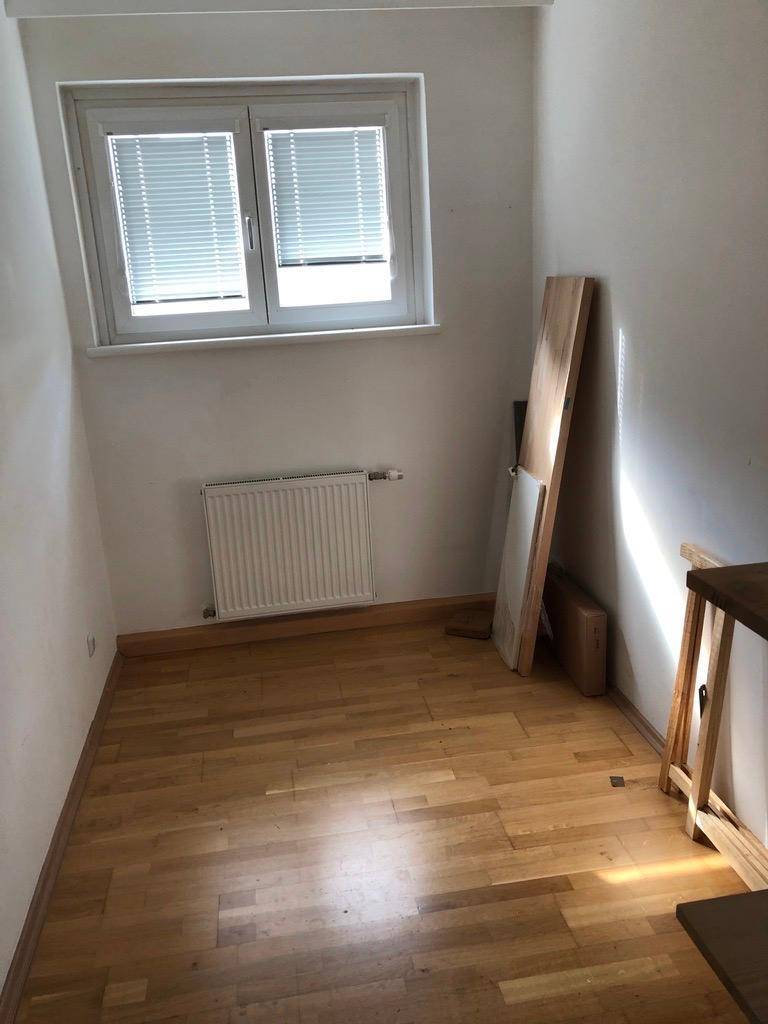 Kleines helles Zimmer mit Holzfußboden und Fenster, gut geeignet als Büro oder Gästezimmer.