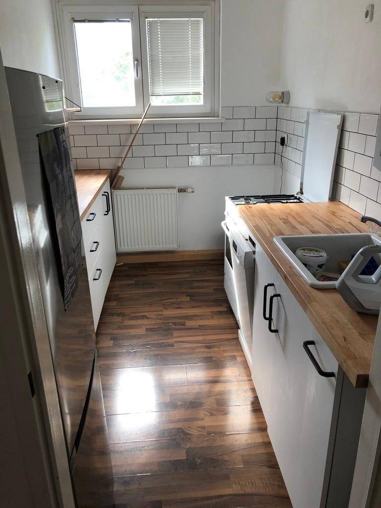 Helle Küche mit Holz-Arbeitsplatten, weißen Unterschränken und gefliester Rückwand.
