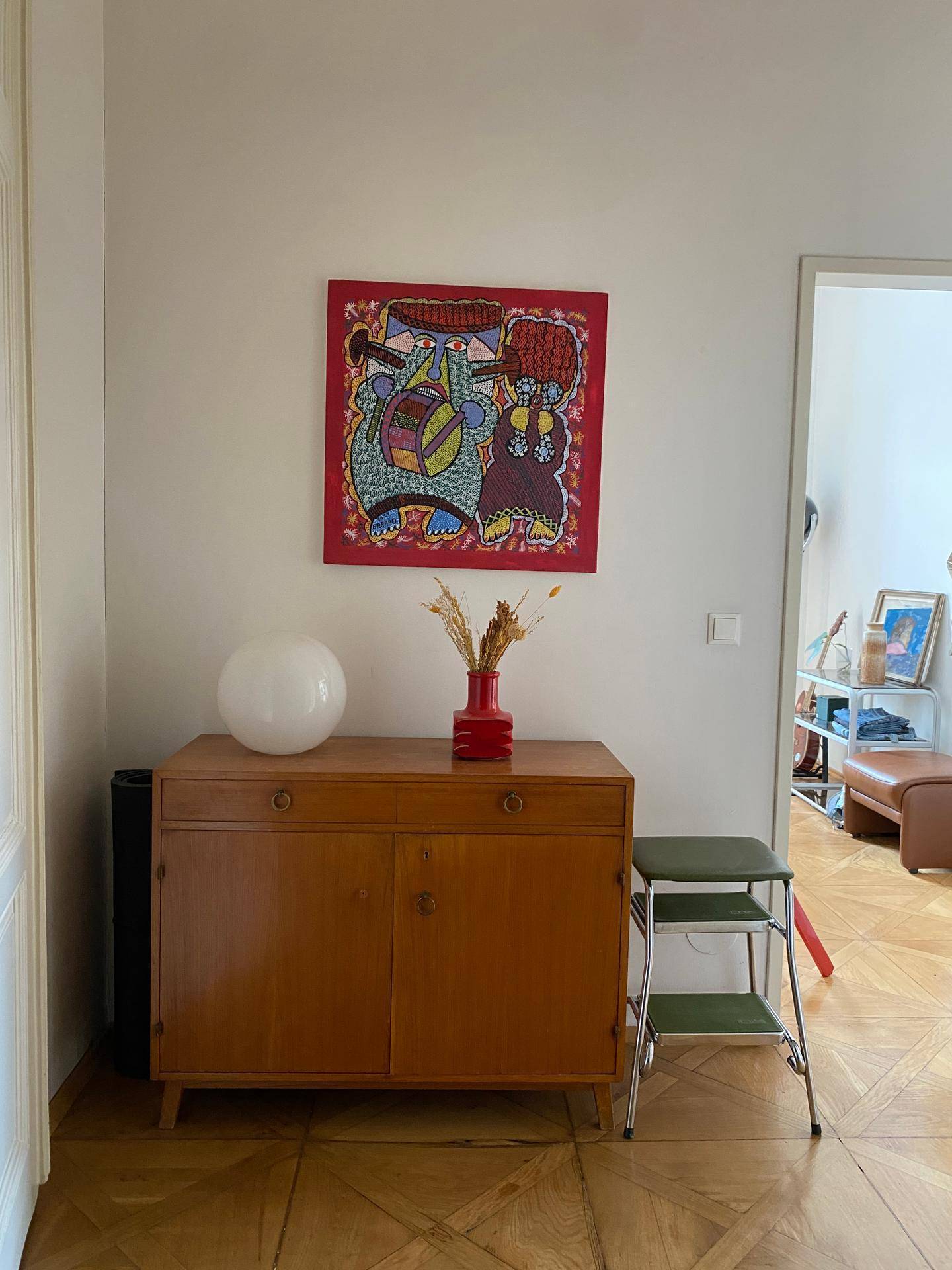 Flur mit einem Holzschrank und einem farbenfrohen Gemälde an der Wand.