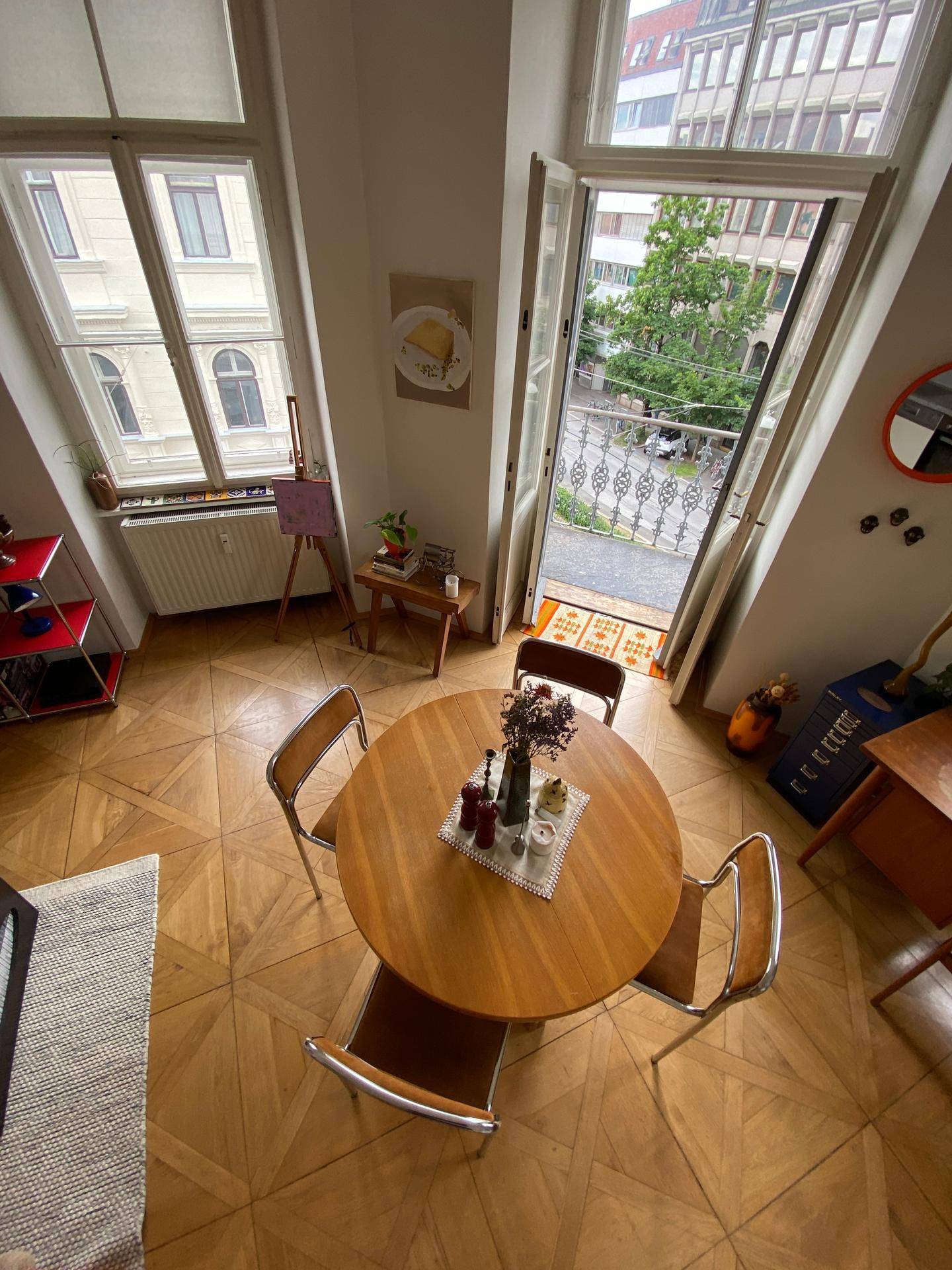 Essbereich mit Holztisch und offenem Balkon, der einen Blick auf die Straße bietet.
