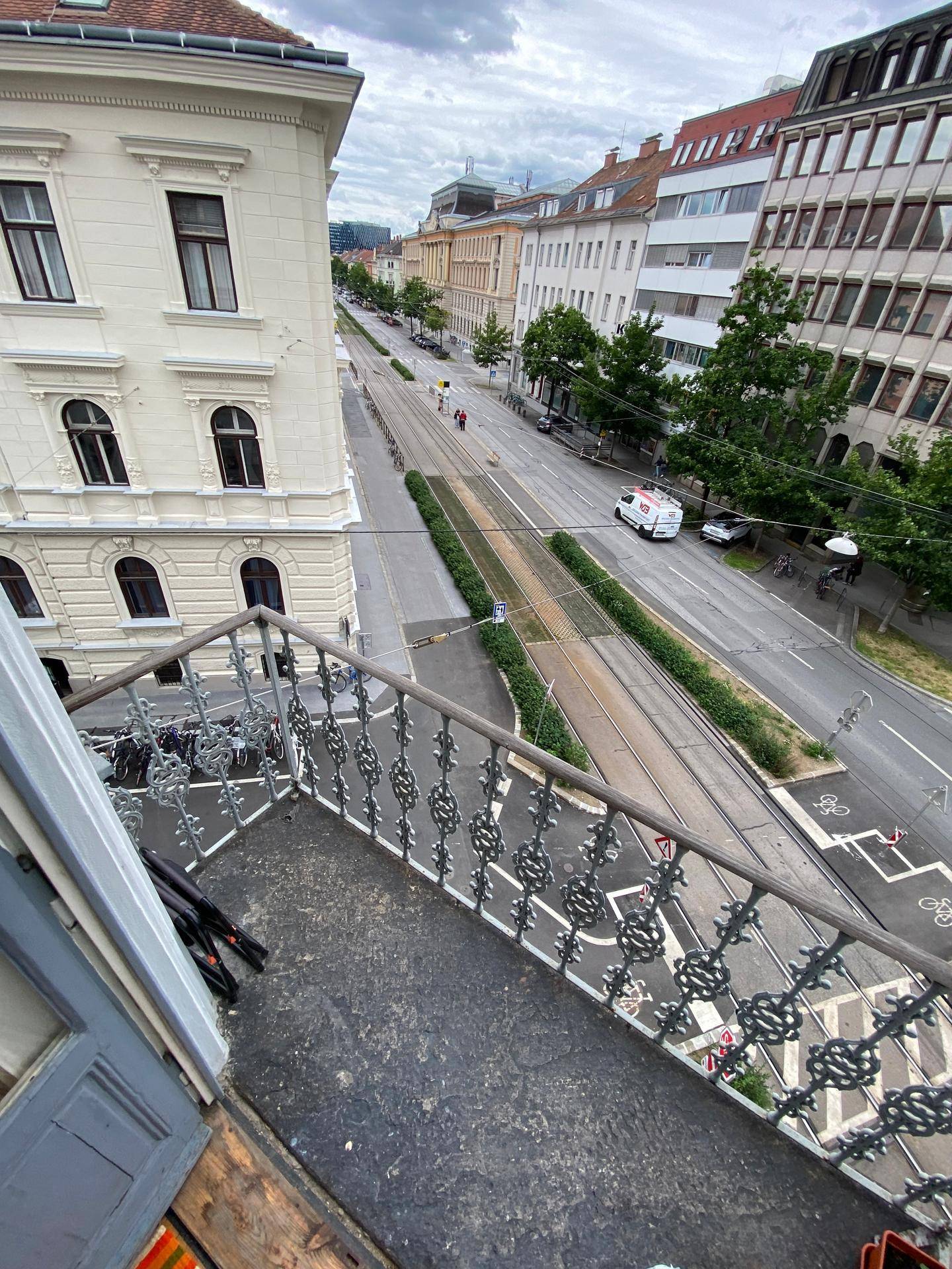Balkon mit schmiedeeisernem Geländer und Blick auf eine belebte Stadtstraße.