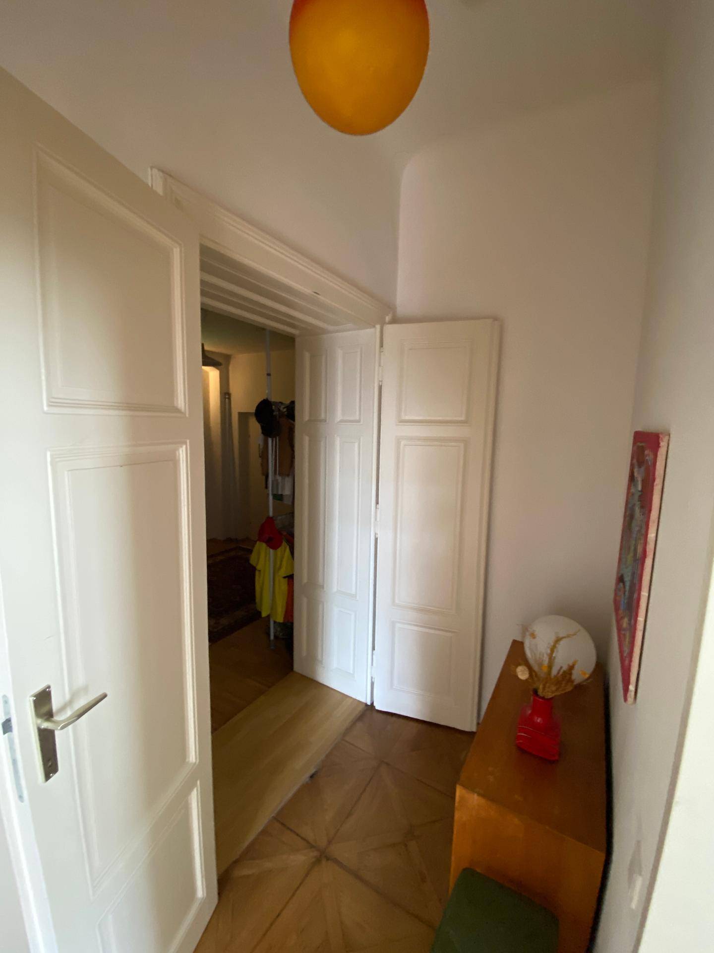Heller Flur mit Holzboden und einem kleinen Schrank, der zu weiteren Räumen führt.