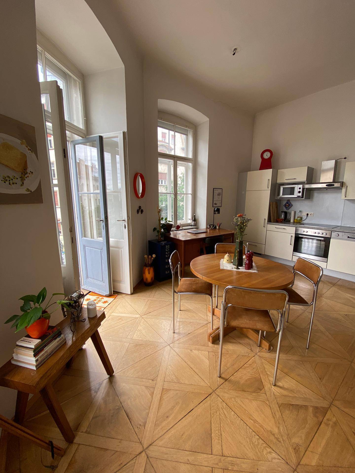 Heller Essbereich mit rundem Holztisch, Stühlen und Zugang zum Balkon.