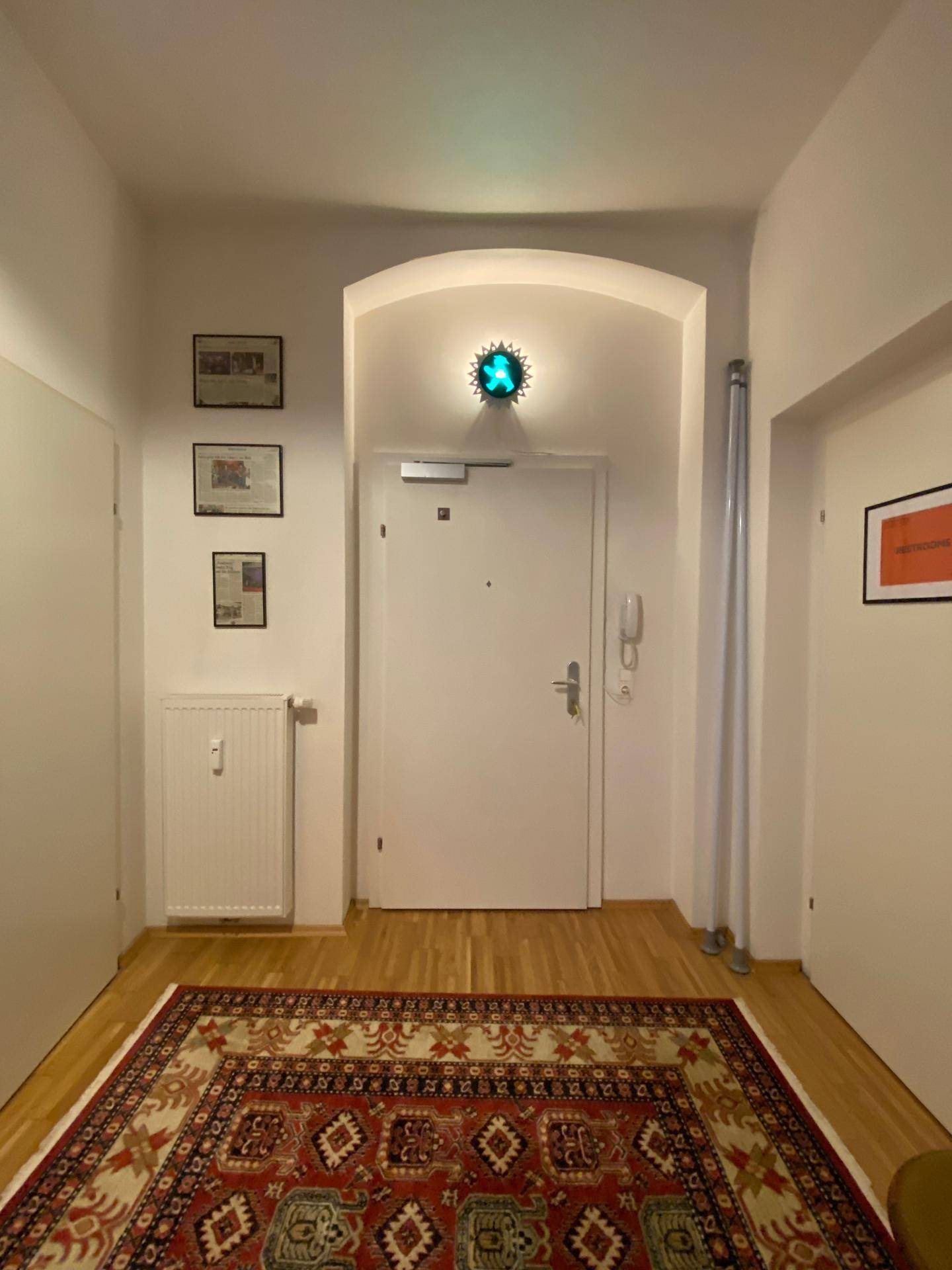 Eingangsbereich mit Haustür, Teppich und einer auffälligen Wandleuchte.