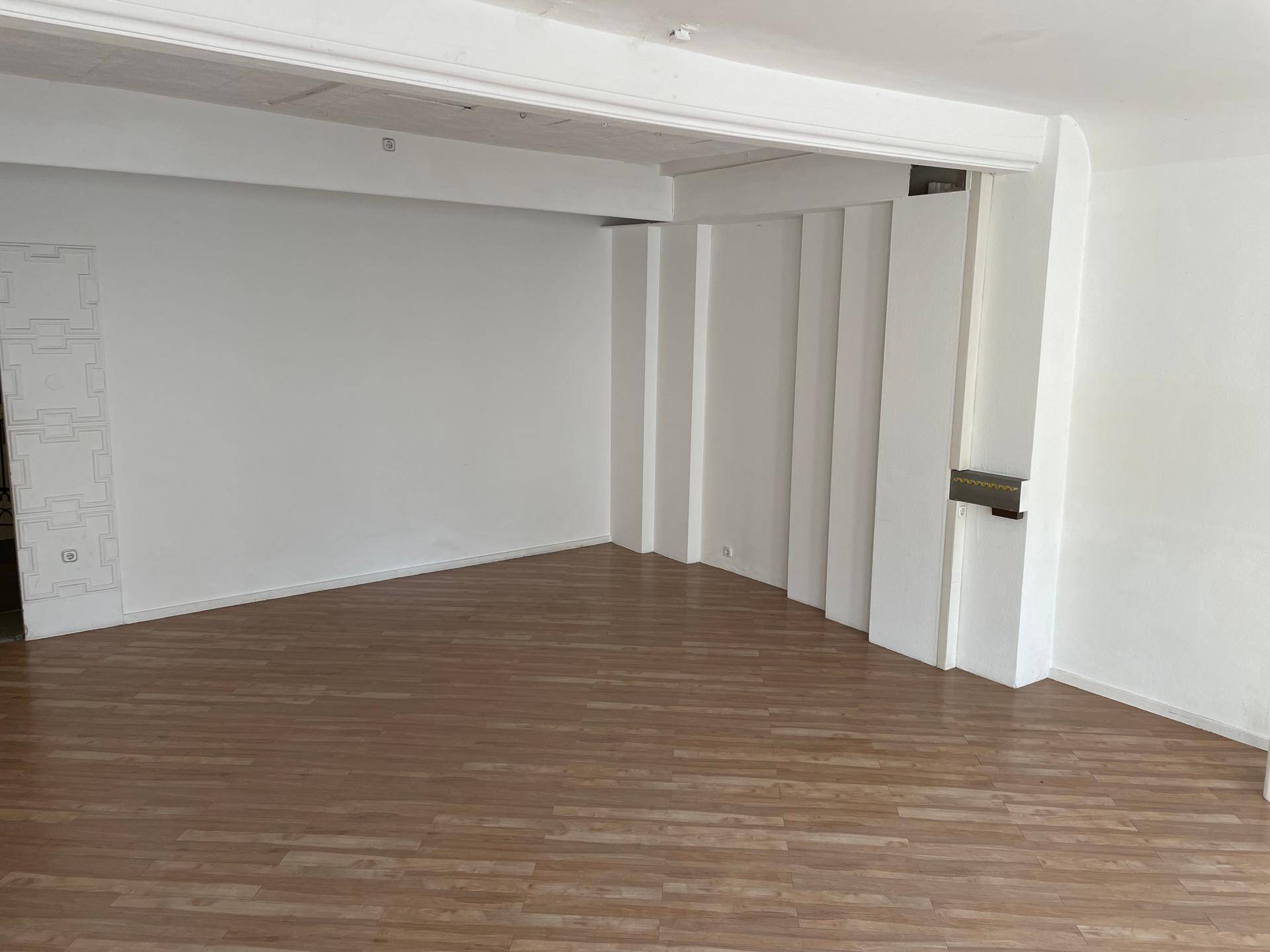 Leerer Innenraum mit hellem Laminatboden und weißen Wänden, ideal für flexible Nutzung in einem Geschäftsbereich.