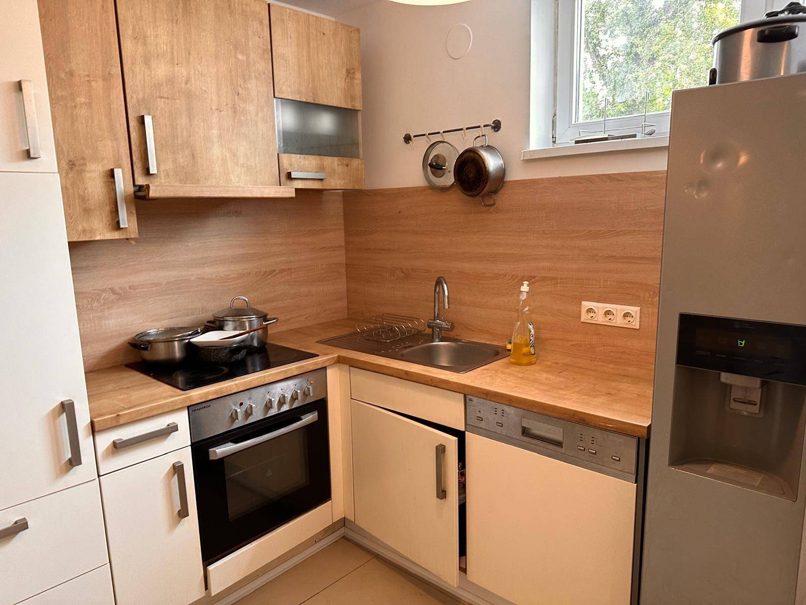 Funktionale Küche mit Holzfronten, Einbaugeräten und einem Fenster für Tageslicht.