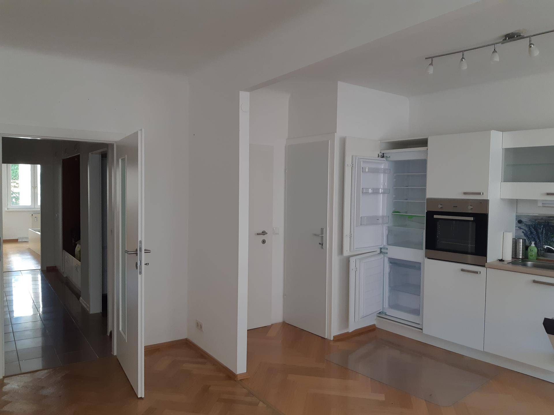Flur mit Parkettboden und Blick in die offene Küche und weitere Räume.