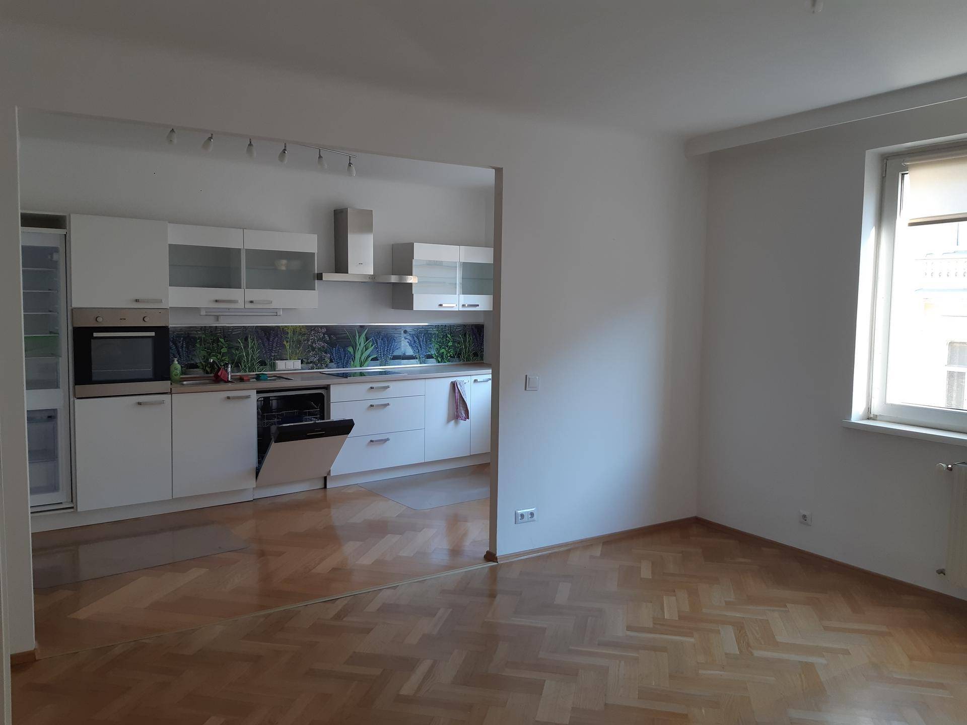 Offener Wohnbereich mit Parkettboden und angrenzender moderner Küche.
