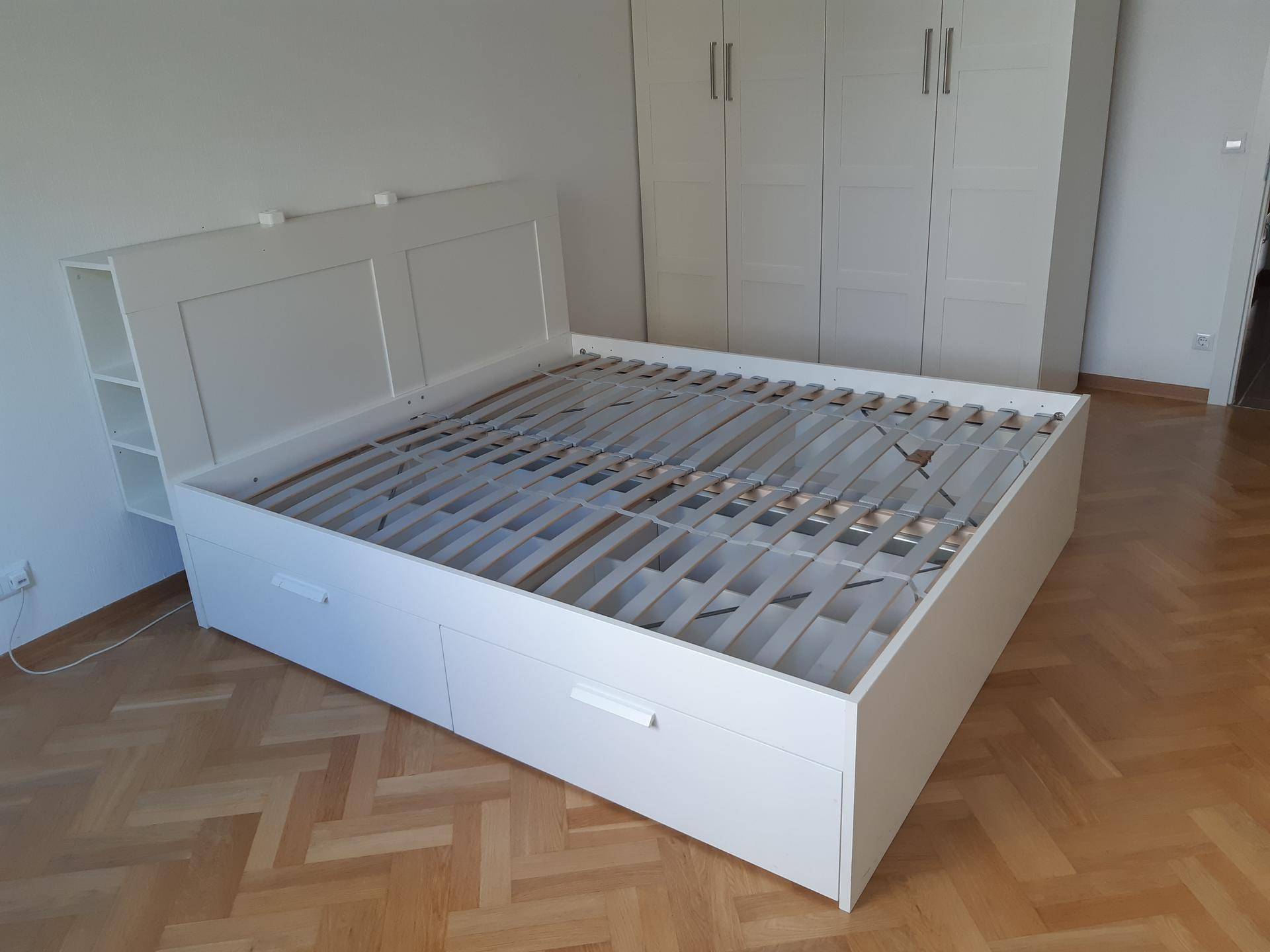 Helles Schlafzimmer mit weißem Bettgestell, integrierten Schubladen und passendem Kleiderschrank.
