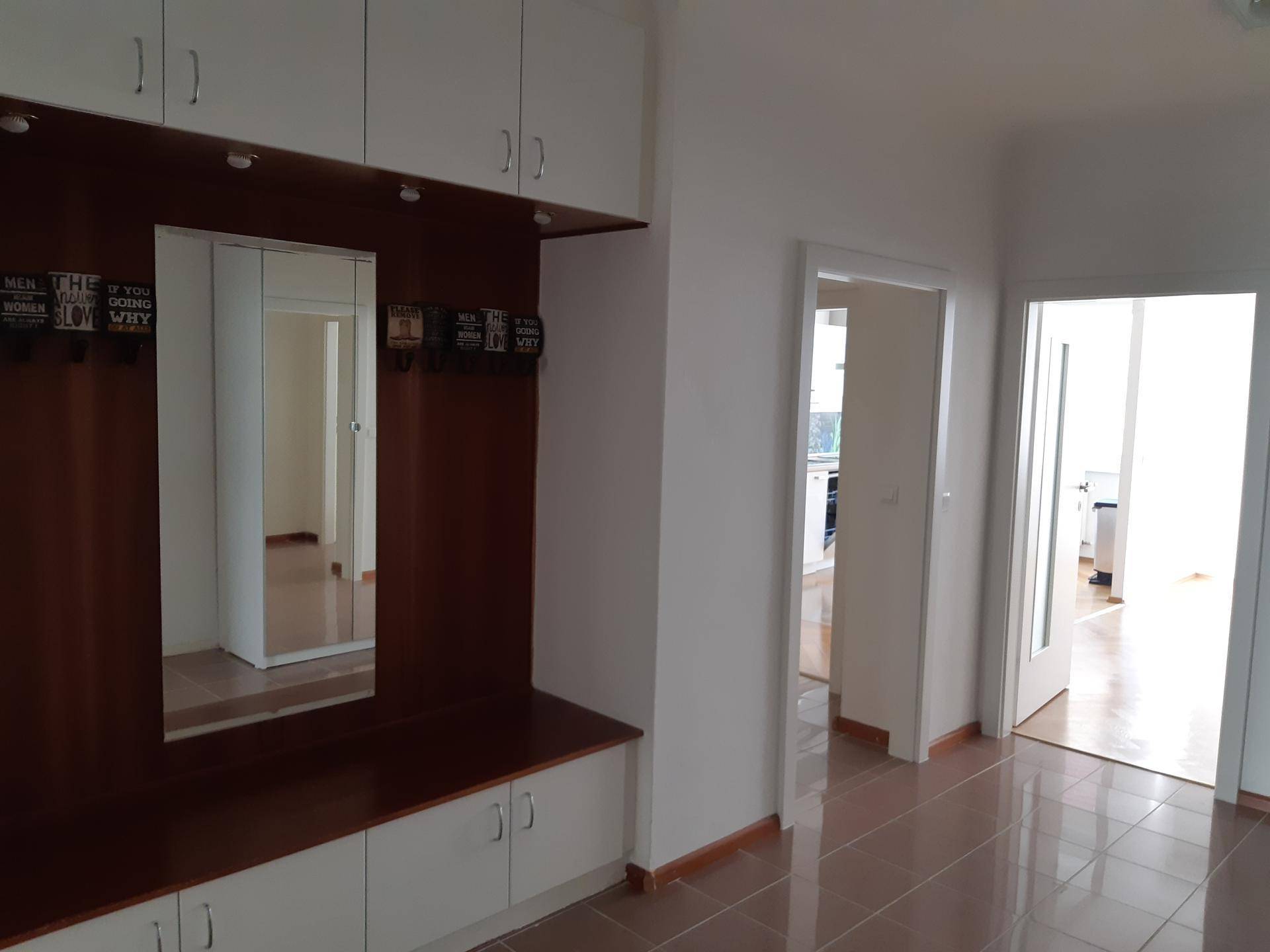 Eingangsbereich mit Fliesenboden, integrierter Garderobe und Spiegel.