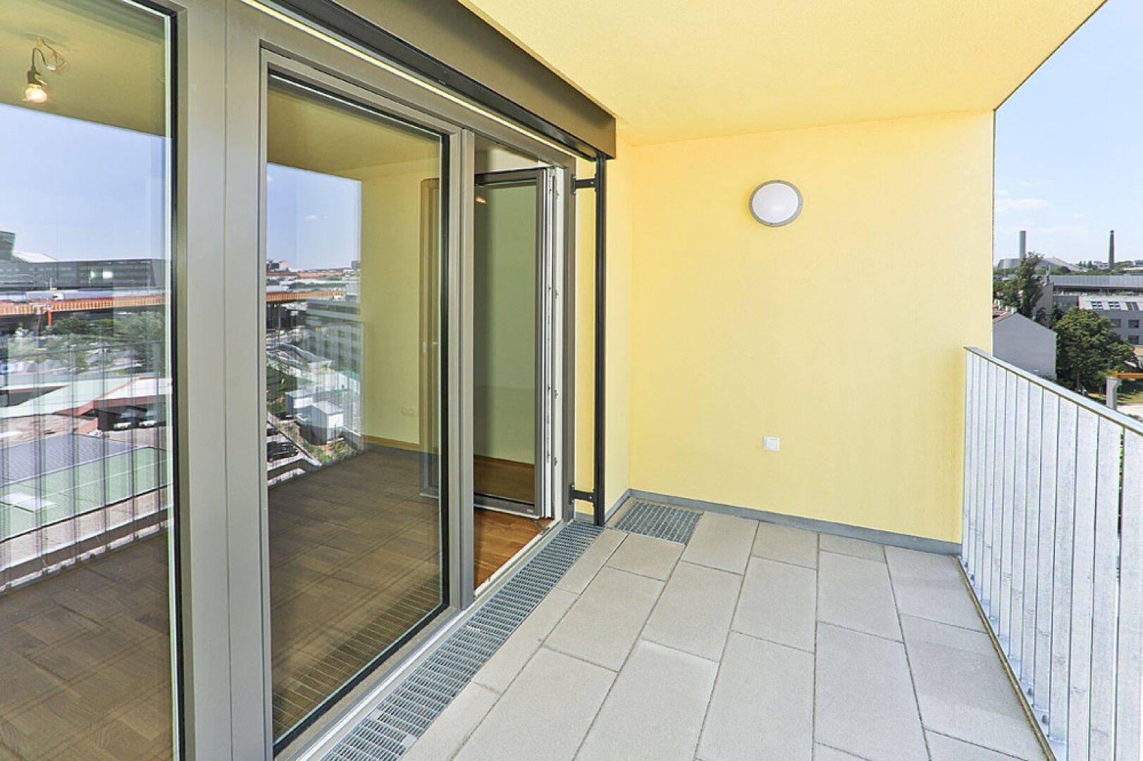 Geräumiger Balkon mit Fliesenboden und Blick auf die umliegende Stadtlandschaft.