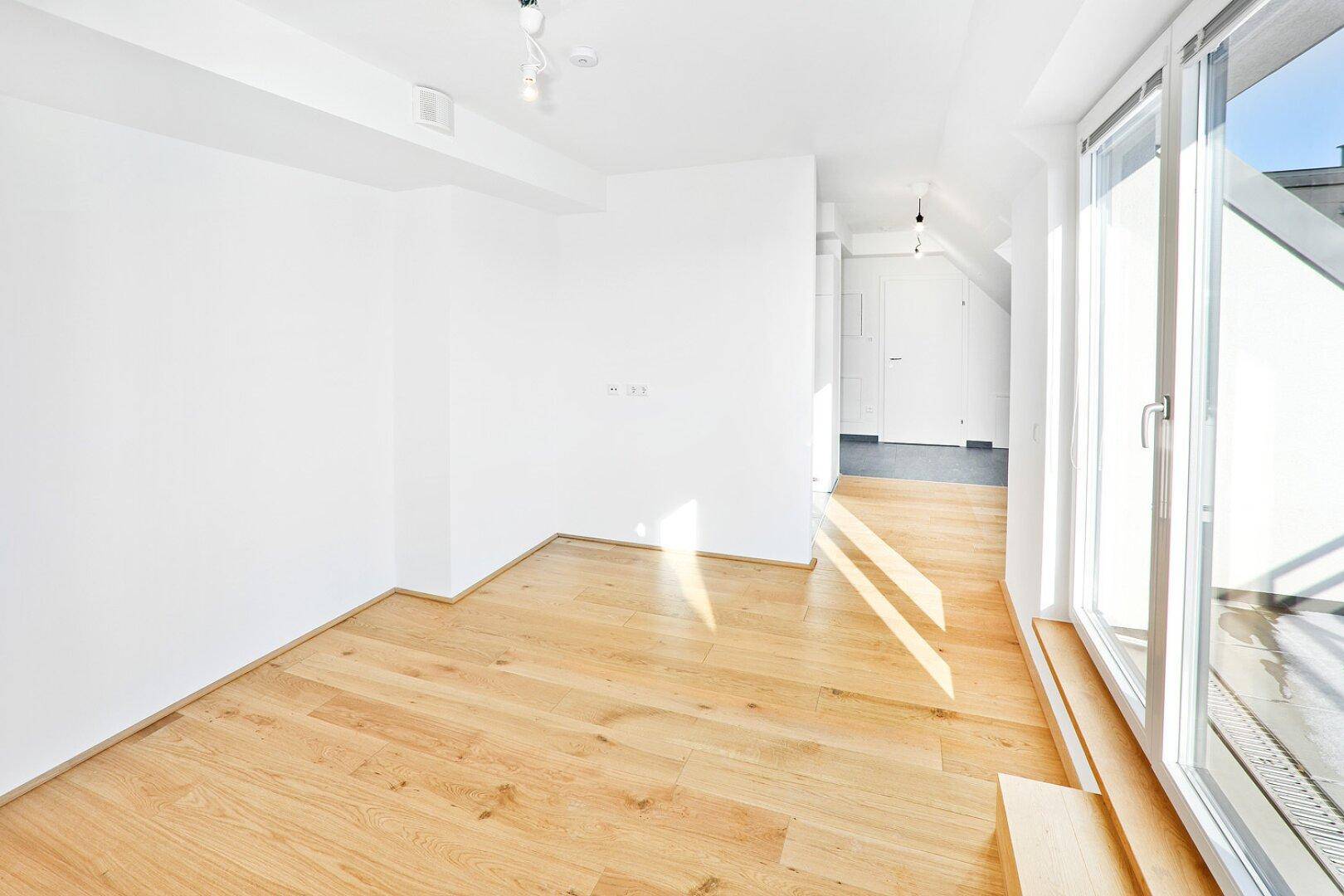 Geräumiger, heller Wohnbereich mit Holzboden und direktem Zugang zur Außenterrasse.