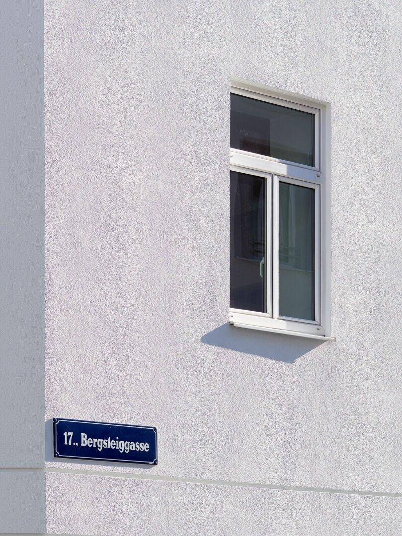 Detailansicht eines Fensters an der weißen Fassade mit Straßenschild "Bergsteiggasse".