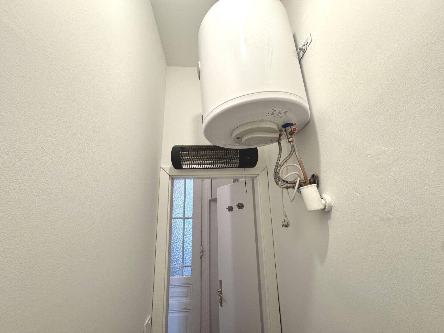 Kleiner Raum mit Warmwasserboiler und Infrarotheizung, ideal als Abstellraum nutzbar.