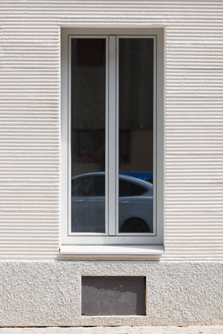 Großes Fenster in einer modernen weißen Fassade mit horizontalen Rillen.