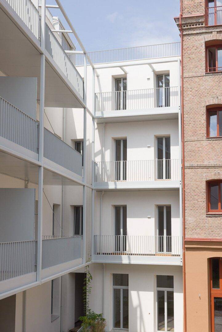 Weiße Fassade eines modernen Wohngebäudes mit mehreren Balkonen und klaren Linien.