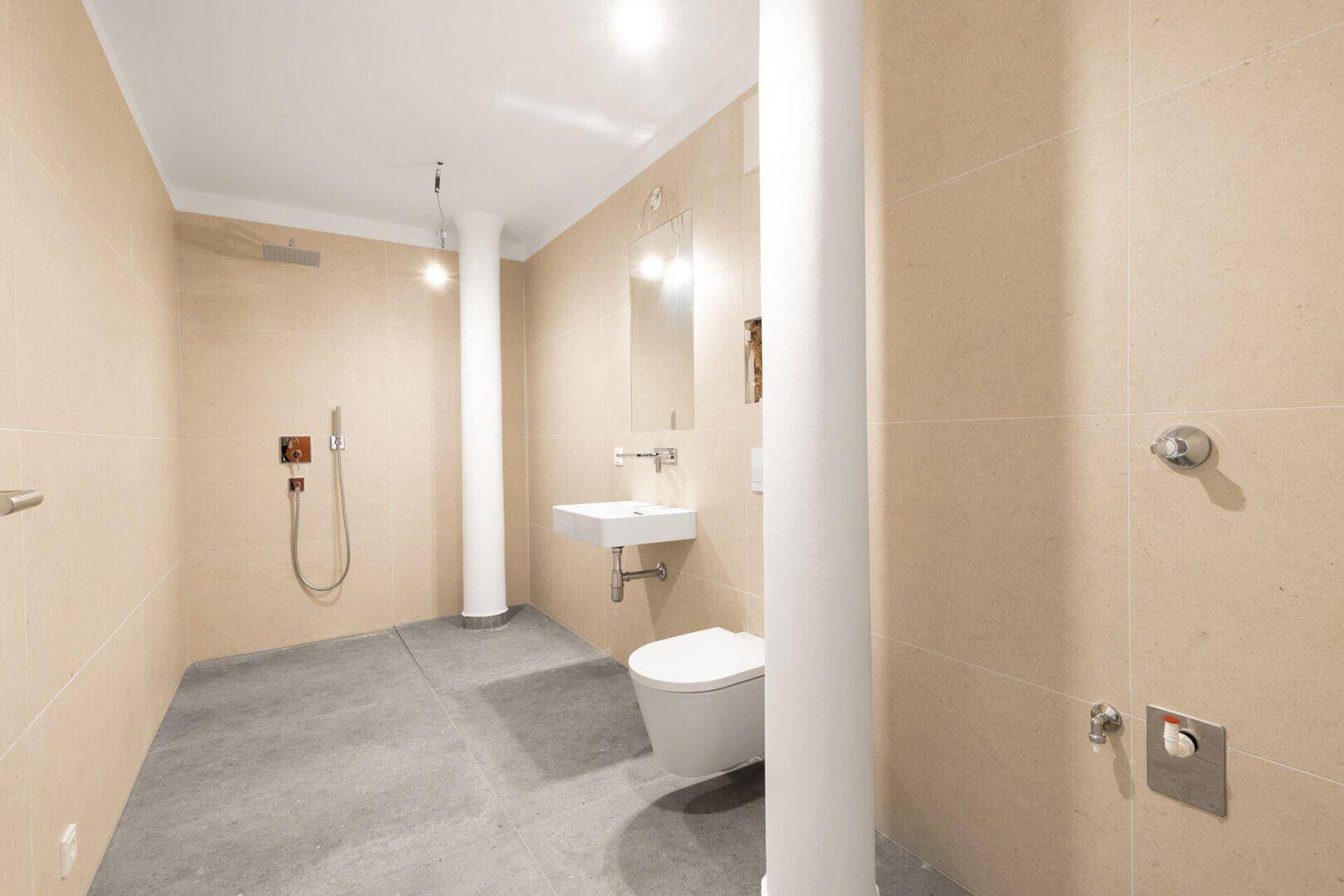 Modernes Badezimmer mit beigefarbenen Fliesen, einer Dusche und einem wandhängenden WC.