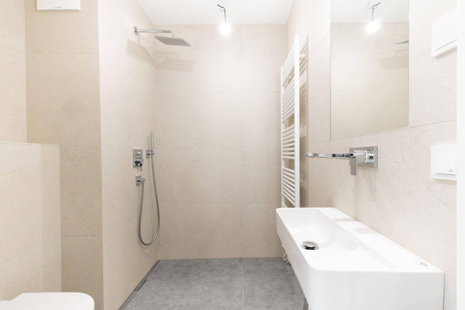 Modernes Badezimmer mit begehbarer Dusche, Wand-WC und beheiztem Handtuchhalter.