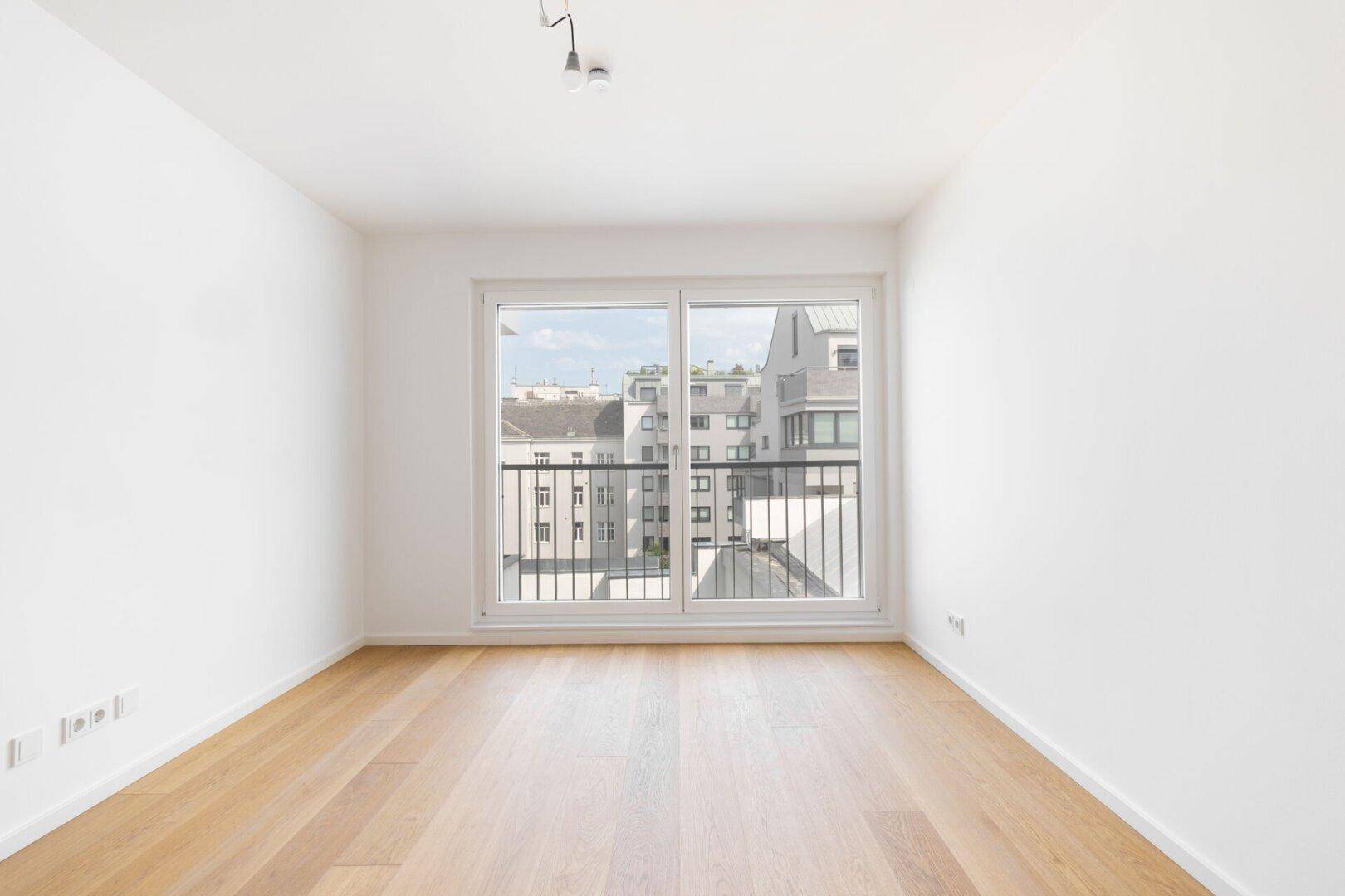 Lichtdurchflutetes Zimmer mit großen Fenstern und Blick auf die Stadt.