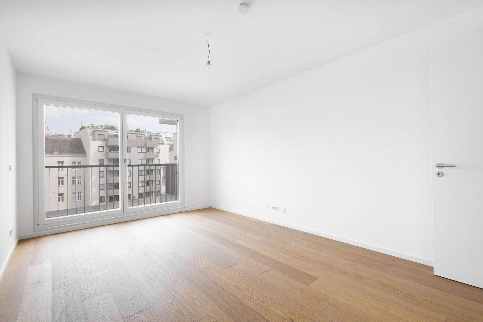 Geräumiges Zimmer mit Parkettboden und breiten Fenstern für viel Tageslicht.