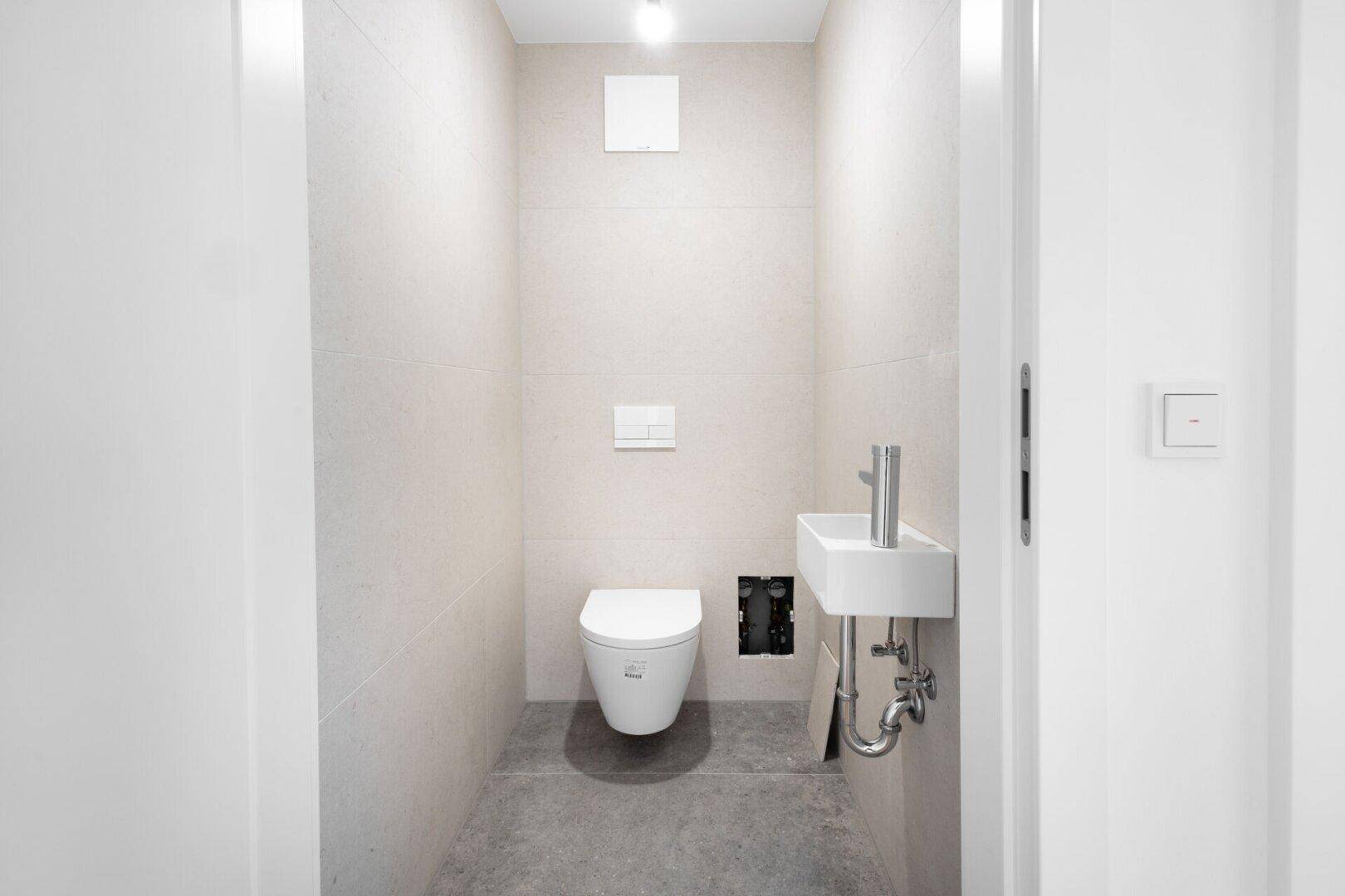 Modernes Gäste-WC mit Wand-WC und kleinem Waschbecken.