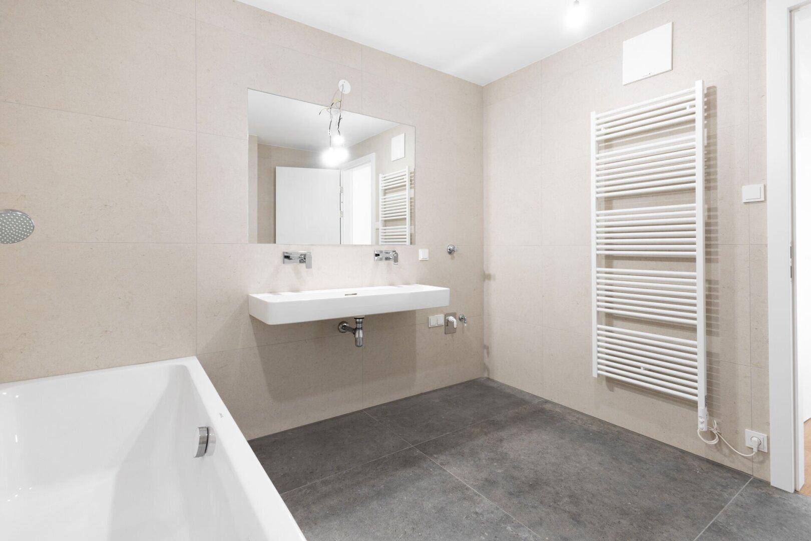 Modernes Badezimmer mit Doppelwaschbecken, Badewanne und beheiztem Handtuchhalter.