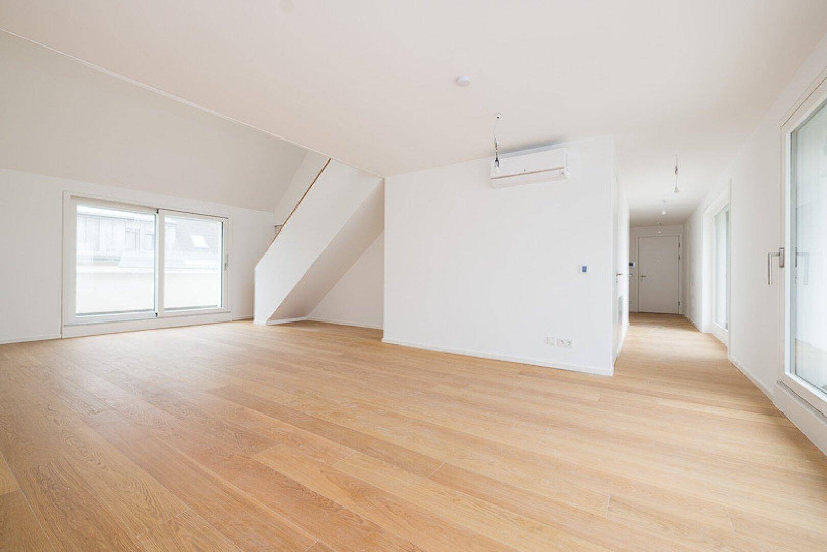 Geräumiger, heller Wohnbereich mit Holzparkett und Zugang zu einem Balkon oder einer Terrasse.