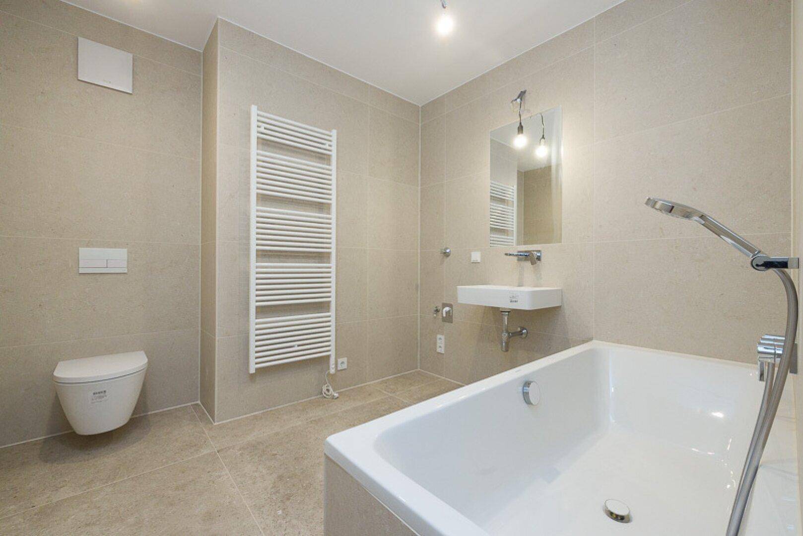 Helles Badezimmer mit Badewanne, wandhängendem WC und beheiztem Handtuchhalter.