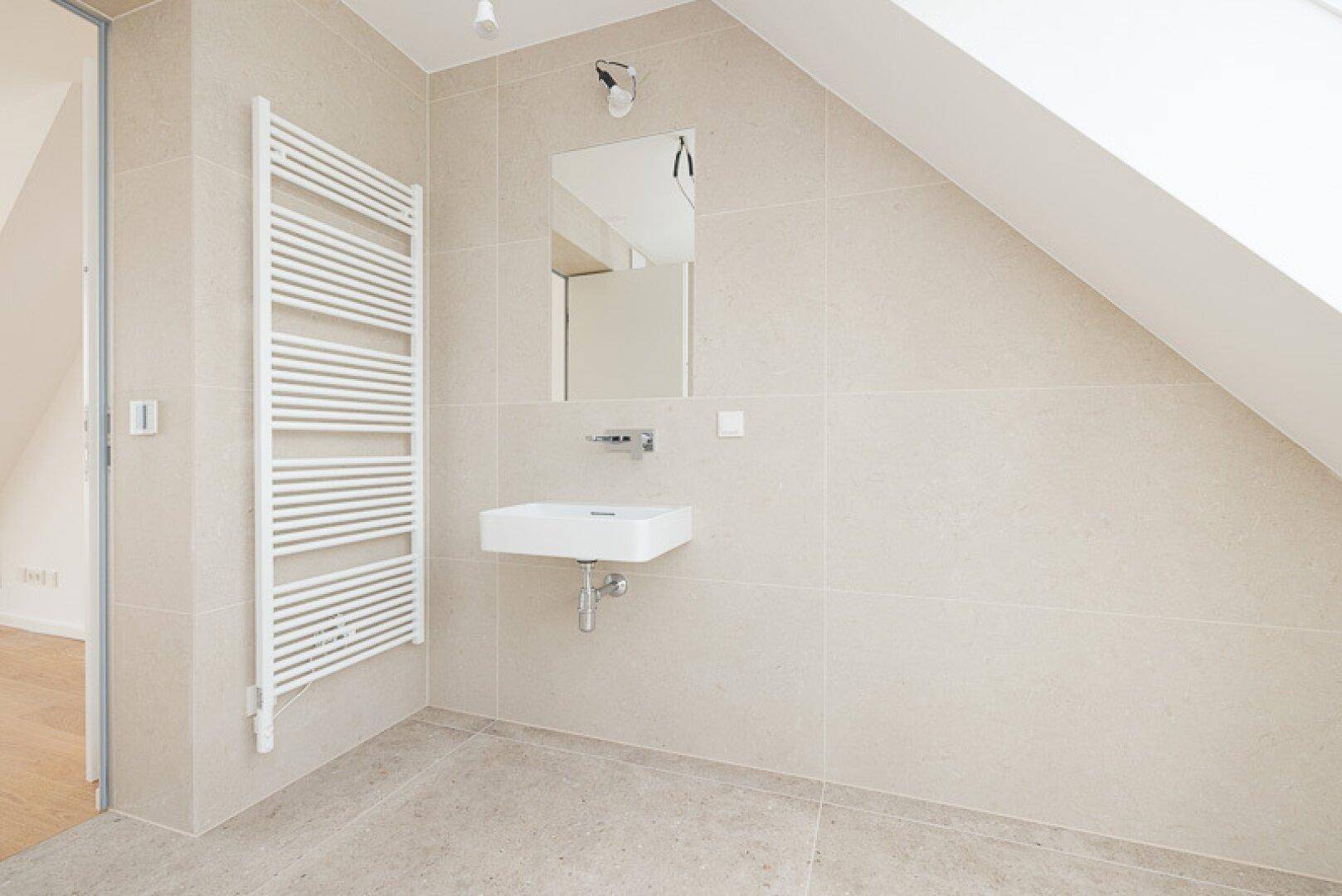 Modernes Badezimmer im Dachgeschoss mit beigefarbenen Fliesen, Waschbecken und beheiztem Handtuchhalter.