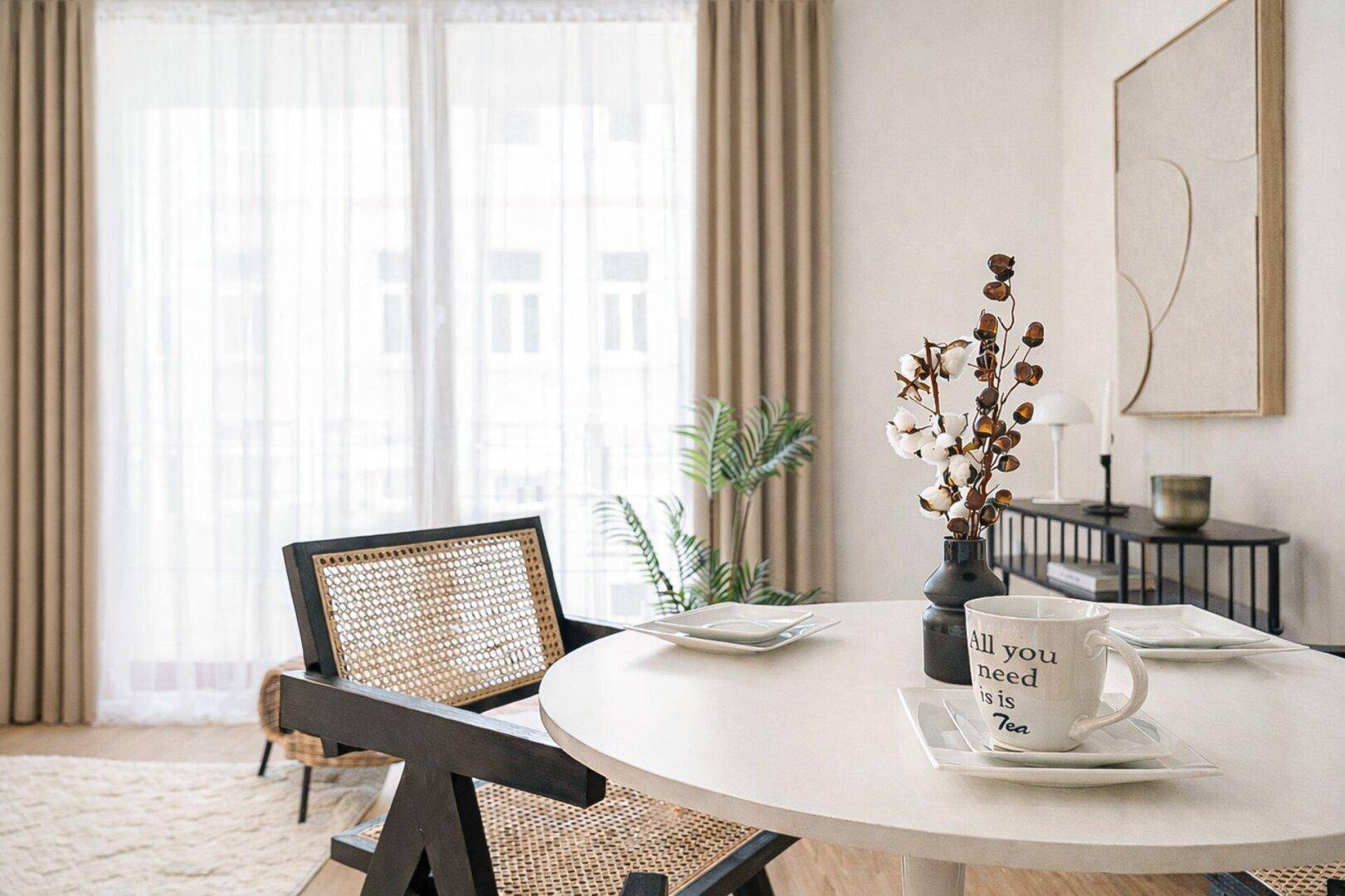 Detailansicht des Essbereichs mit modernem Tisch, Rattan-Stuhl und Blick auf die großen Fenster.