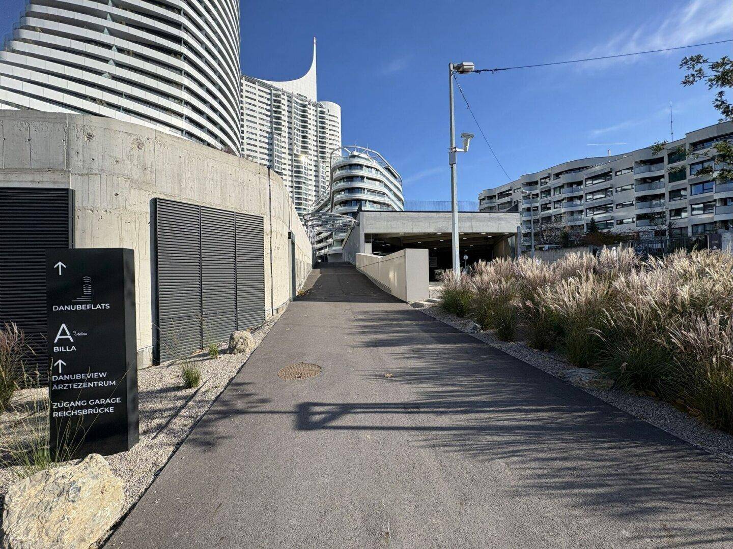 Moderne Architektur mit geschwungenen Linien und Zugang zur Tiefgarage in urbaner Umgebung.
