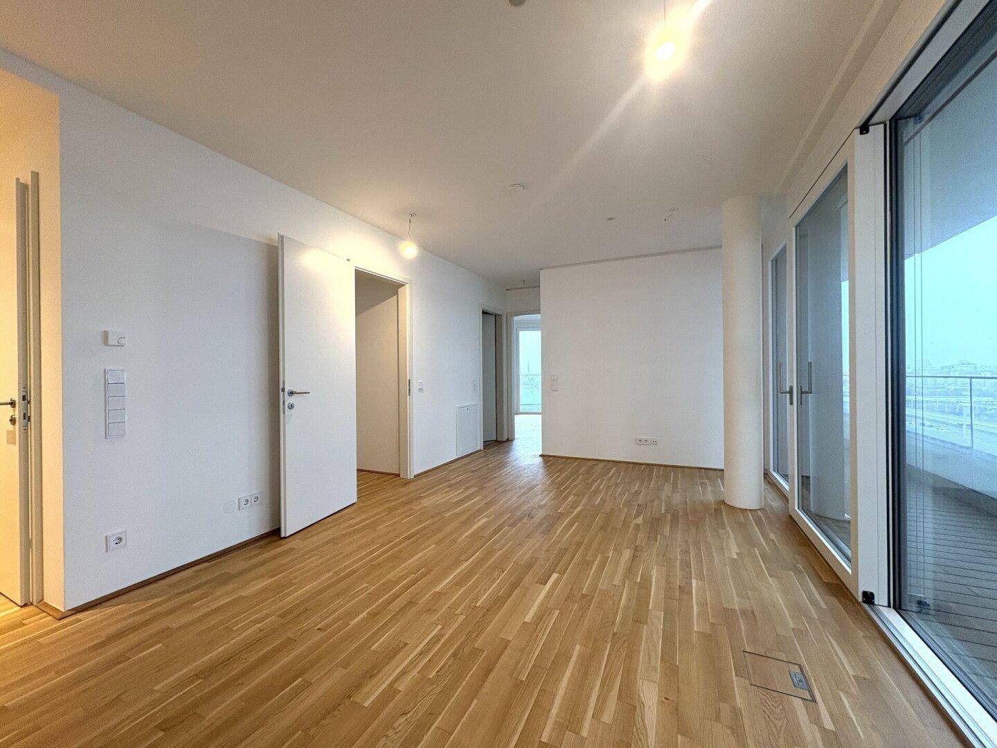 Geräumiger offener Wohnbereich mit Eichenparkett und großen Fenstern, die viel Licht hereinlassen.