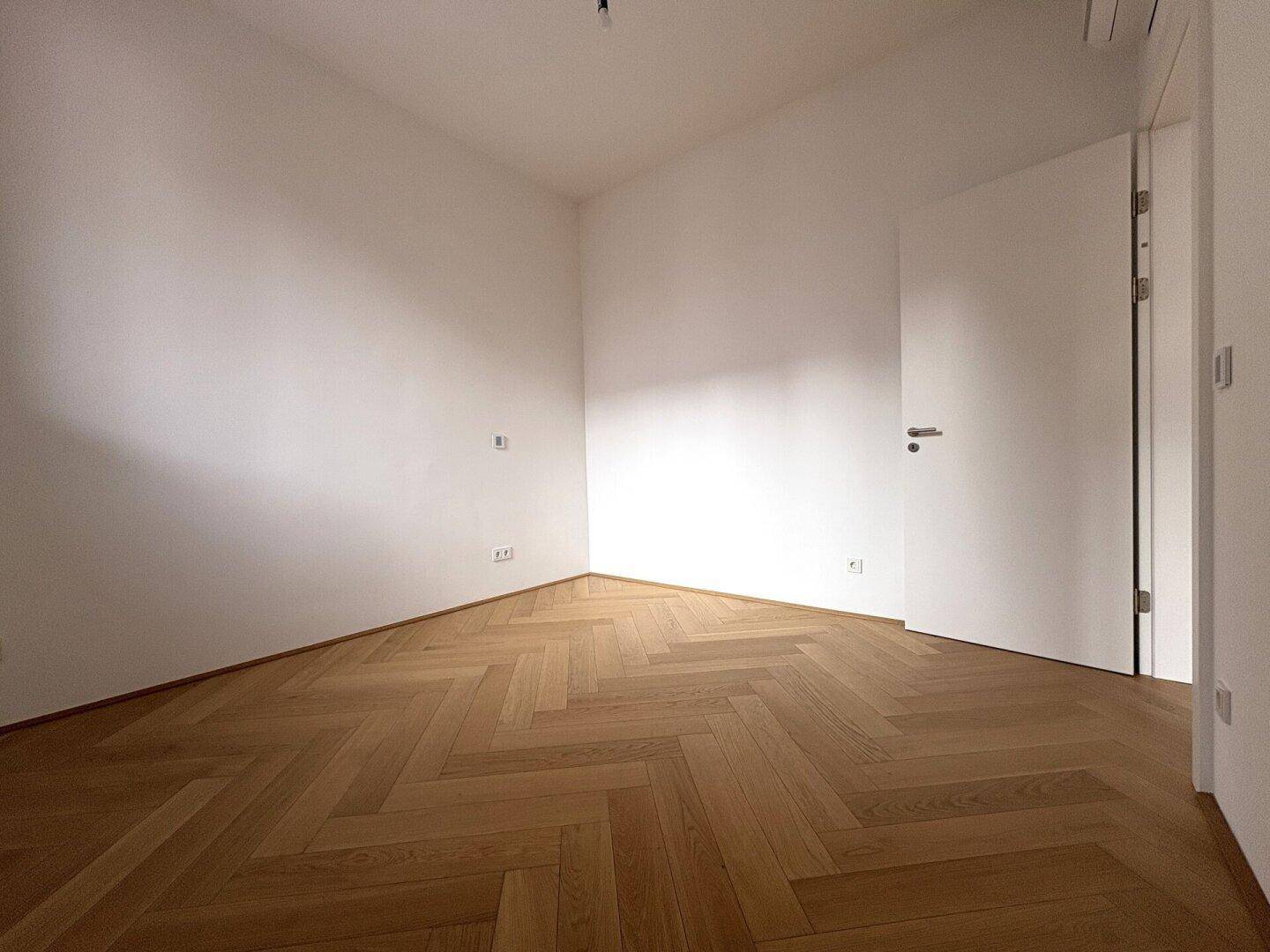Helles Zimmer mit Fischgrätparkettboden, bereit zur individuellen Gestaltung.