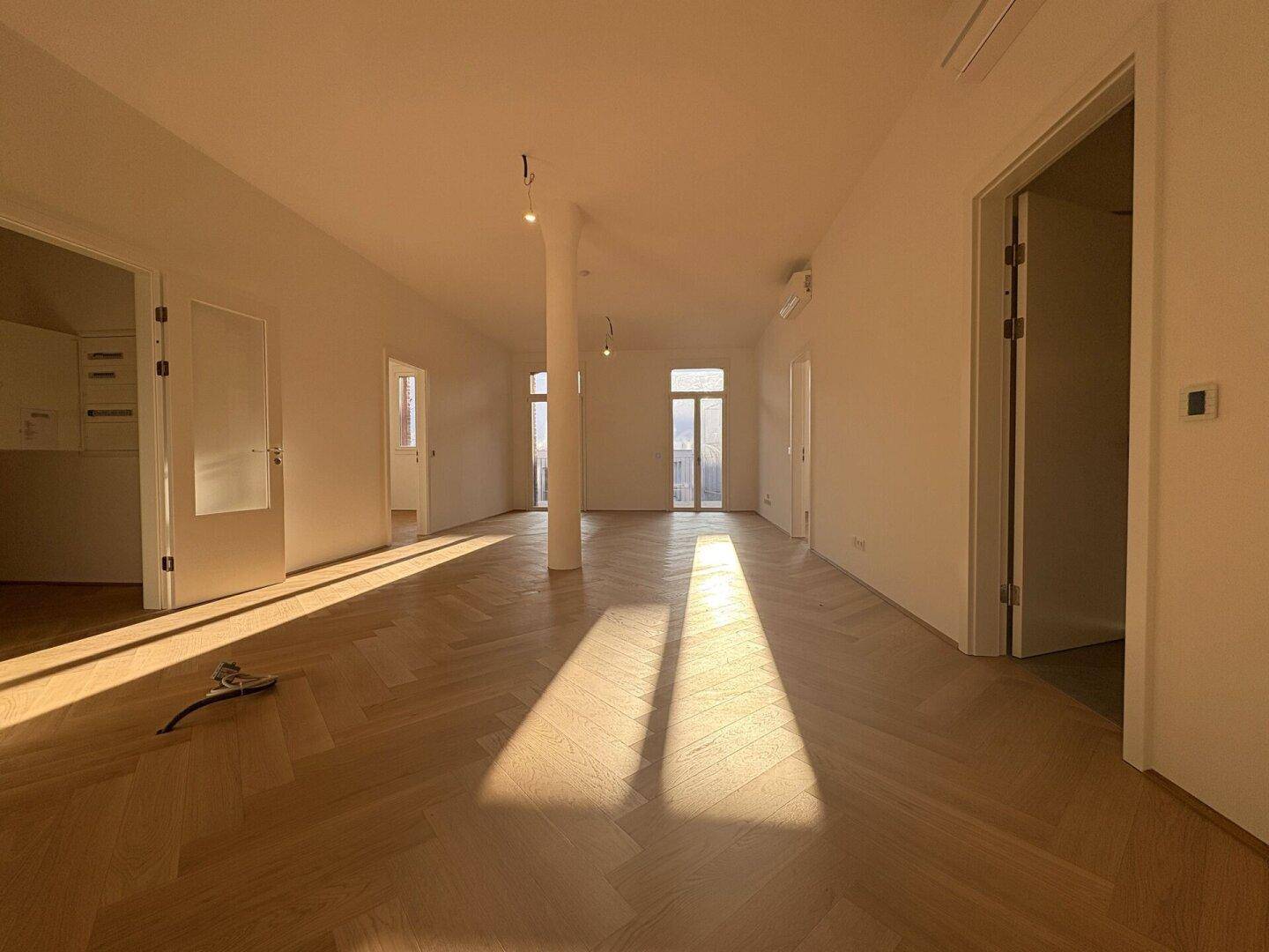 Heller, offener Wohnbereich mit Fischgrätparkett, hohen Decken und viel natürlichem Licht.