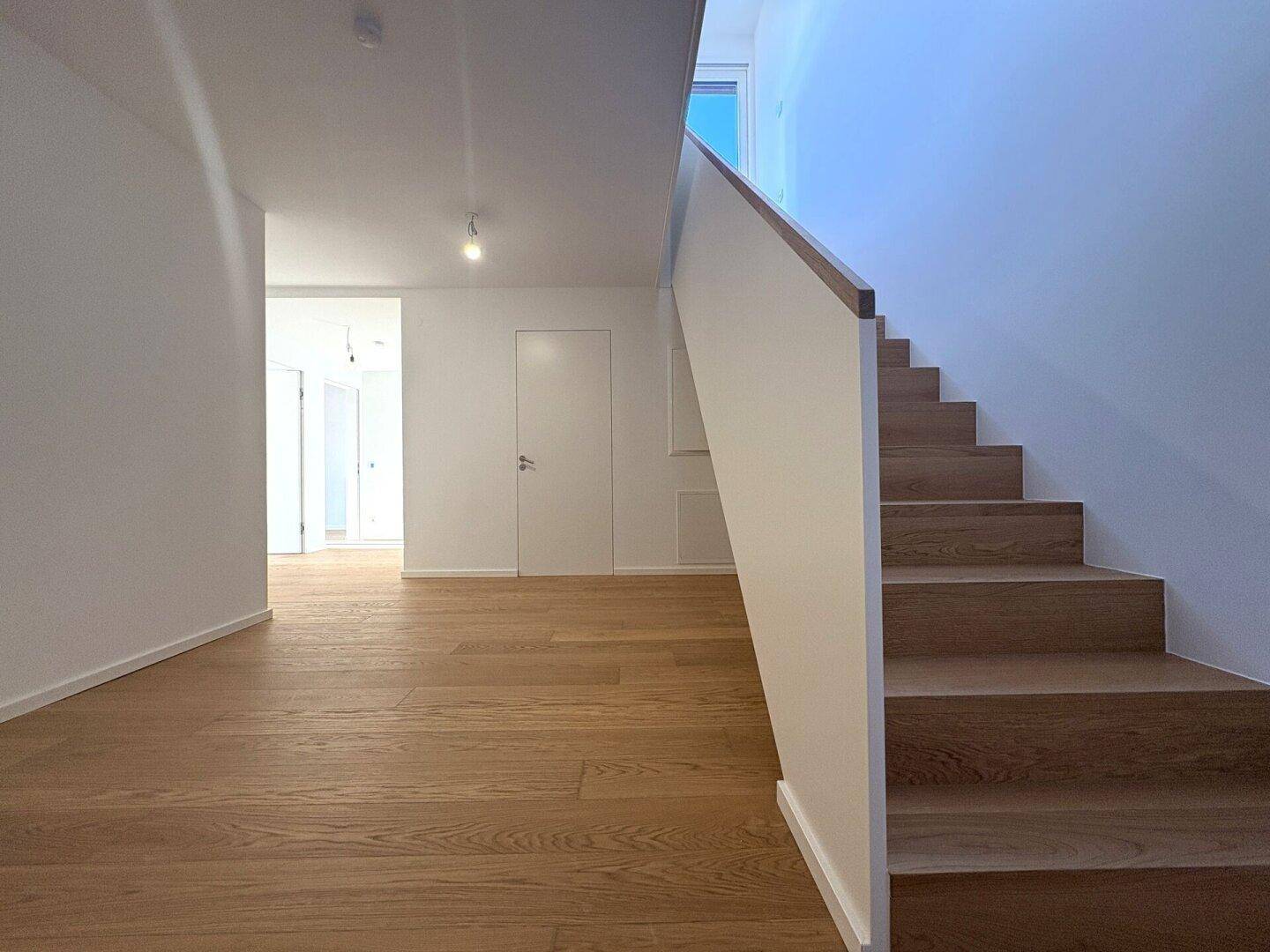 Geräumiger Flur mit Holzparkett und einer modernen Treppe, die in die obere Etage führt.