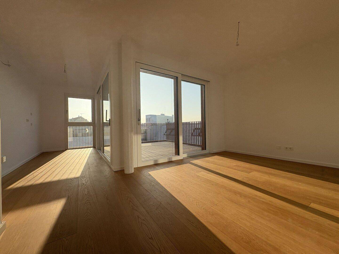 Lichtdurchfluteter Wohnbereich mit Holzboden und weitem Blick durch große Fenster.