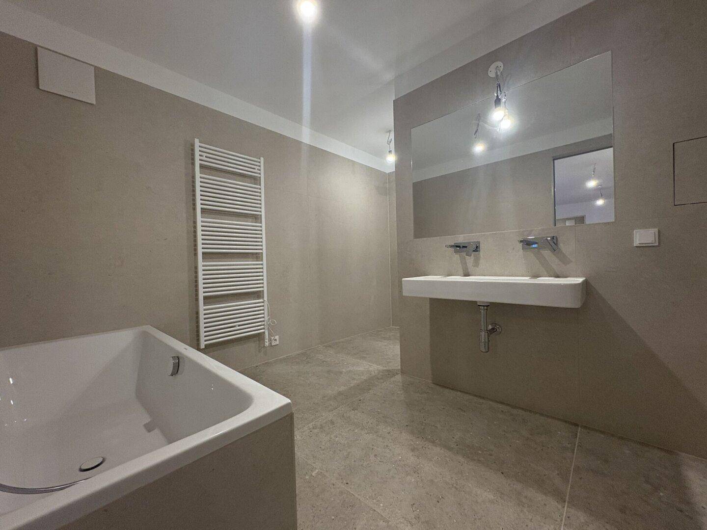 Modernes Badezimmer mit Doppelwaschbecken, Badewanne und beheiztem Handtuchhalter.