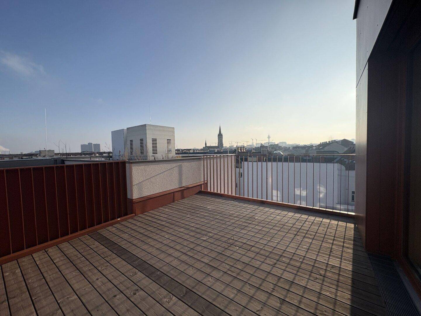 Große Dachterrasse mit Holzboden und weitem Blick über die Stadt.